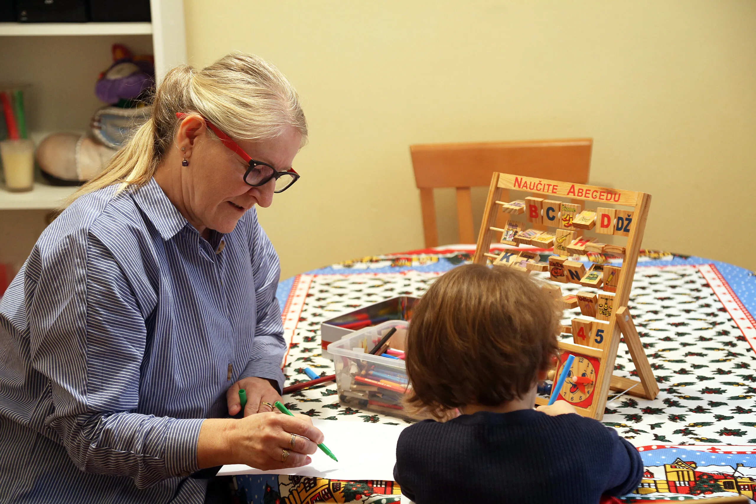 SOS mama Gordana pomaže pisati zadaću djevojčici koja odrasta u SOS Dječjem selu Lekenik